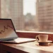 Laptop with financial chart and coffee cup on desk. Financial autonomy workshop.