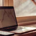 Transitioning from savings to investing. Laptop with stock chart, calculator, and plant.